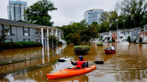 Erik Lesser/EPA-EFE Peachtree Park Apartments resident Candice Ocvil (left) and Jibri Tolenrow through flood waters from Peachtree Creek, Georgia