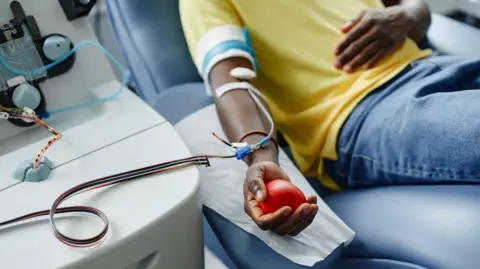 Man holding soft ball and donating blood at center - stock photo.