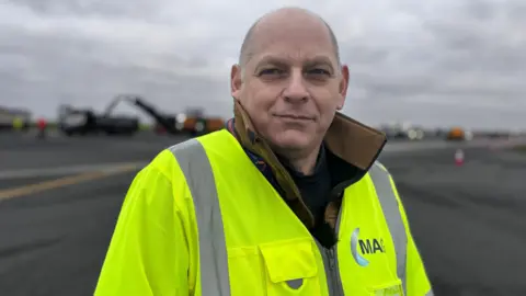 A picture of a man wearing a high-vis jacket at East Midlands Airport