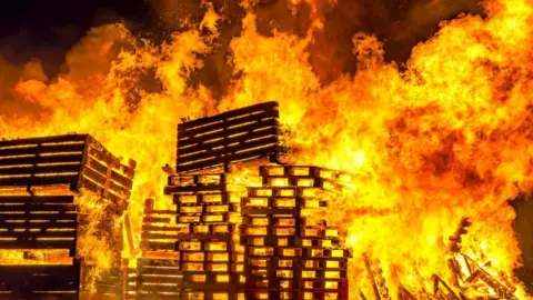 The silhouettes of wooden crates seen in a large fire