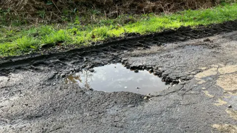 Pothole in road filled with water 
