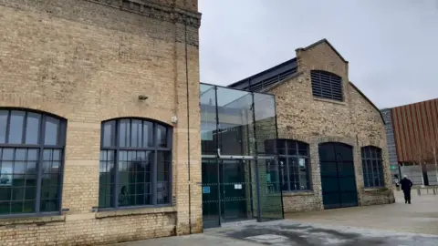 Sand Martin House is a large brick building with large windows and a glass atrium at the entrance
