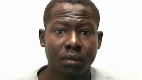 North Yorkshire Police A custody photo of a man who looks directly at the camera. He sits in front of a white background, has short dark hair and is wearing a grey jumper.