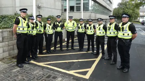 A group of police officers in high visibility tops and black uniforms stands outside Scottish Borders Council's headquarters
