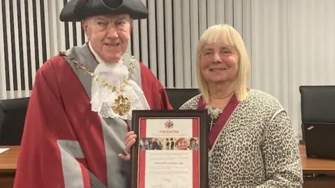 Margaret Aspinall with Mayor of Knowsley Councillor Ken McGlashan holding a framed Freedom of the Borough award