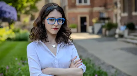 Francesca Gardner is standing with St Catharine's College, Cambridge in the background.