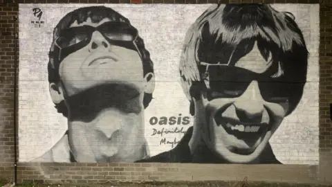 Pic.One.Art A large black and white mural featuring Noel Gallagher looking up and Liam Gallagher smiling, with the words 'Oasis Definitely Maybe' and Pic.One.Art's tag