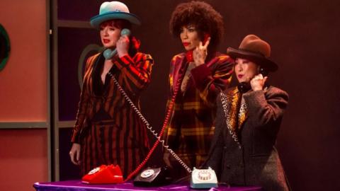 The Showwomen posed in costume holding telephones