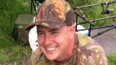 Merseyside Police handout Undated handout photo of the late Paul Smith. He is wearing camouflage patterned baseball cap and t-shirt with fishing equipment in the background. He is smiling.