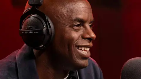 Trevor Nelson smiling while speaking into a radio mic
