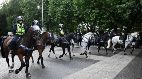 Getty Images A line of mounted police officers in riot gear seen moving through central Bristol. 