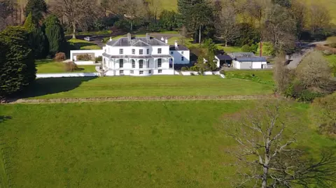 Gilliland family Shows a large white mansion surround by trees 