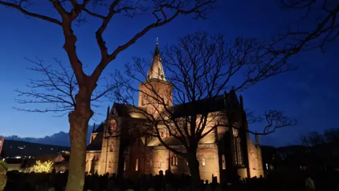 Matthew Wylie  St Magnus Cathedral lit up at night, with trees in front of the building