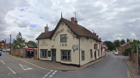 A cream-coloured pub with "Rampant Horse Inn" written on the side of it