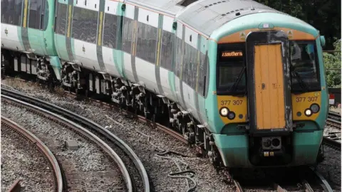 A green and white Southern train travels along a track