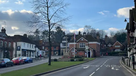 An image of Haslemere high street. You can see shop fronts and a war memorial. 