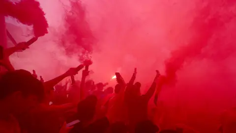 PA Media Liverpool fans set off red coloured flares outside Anfield