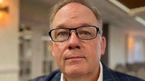 Man in glasses in a suit in a conference room