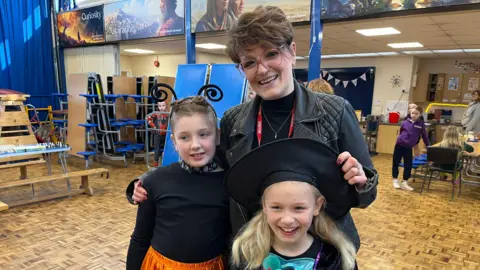 Two children in fancy dress and their mum.