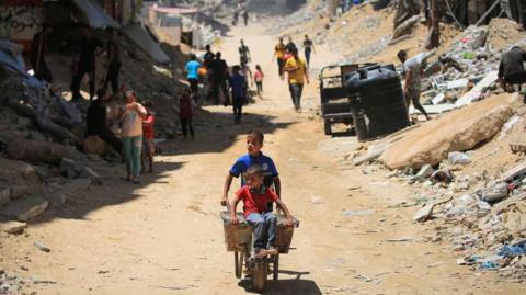 A young boy wheels a wheelbarrow through Gaza