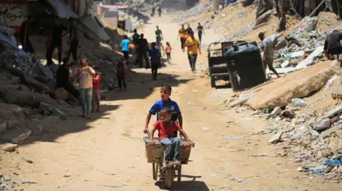 Getty Images A young boy wheels a wheelbarrow through Gaza