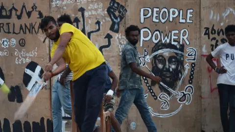 Getty Images Demonstran antipemerintah bermain kriket di tenda kamp protes dekat Sekretariat Presiden di Kolombo pada 23 Juli 2022. 