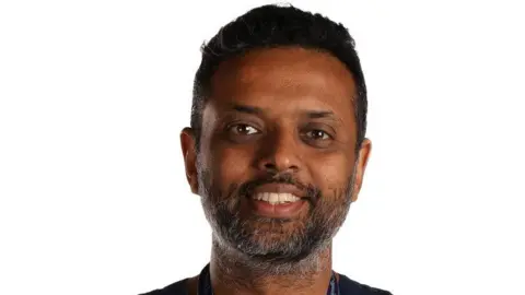 The Royal Wolverhampton NHS Trust Professor Tonny Veenith - a man with short black hair, a black and grey short beard and moustache is smiling at the camera against a white background