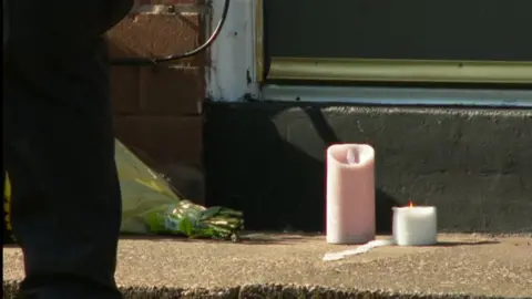 Two candles, one pink and white, sitting outside a house