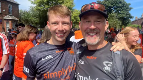 Two men in Armagh jerseys standing with their arms round each other smiling at the camera