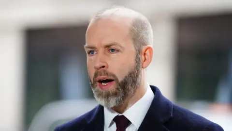 PA Media Business Secretary Jonathan Reynolds wearing a blue suit with a white shirt and maroon tie talking to the media outside BBC Broadcasting House in London, after appearing on the BBC One current affairs programme, Sunday with Laura Kuenssberg. 