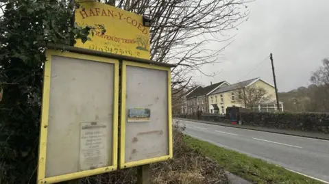 A yellow sign surrounded by leaves bearing the words Hafan-y-Coed