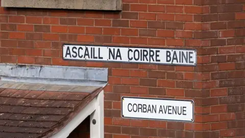 Pacemaker Signs in Irish and English relating to Corban Avenue on a brick property in Enniskillen.