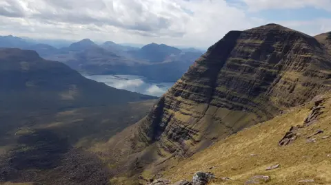 Catriona Webster. Una vista impresionante de un paisaje de montañas y un lago. En primer plano se encuentra la montaña Beinn Alligin.