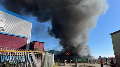 Phil Harrison / BBC A plume of smoke over some industrial estate buildings.