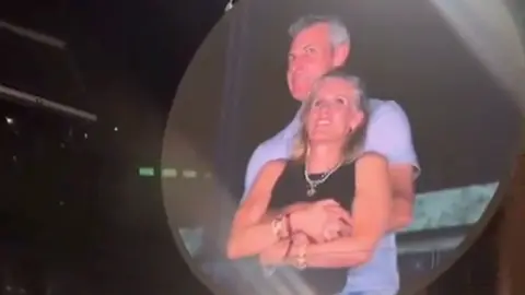 A man and a woman embrace on a big screen