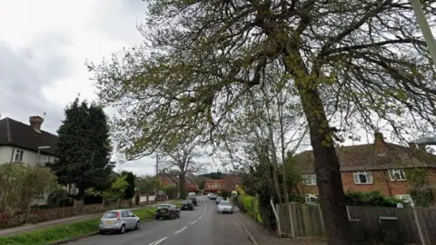 Google A street with cars and trees on it.