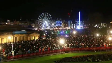 PA People pack the streets in Edinburgh city centre. The Ferris wheel is in the background.