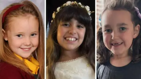 Family Handouts Headshots of three young girls. One on the left is dressed in a maroon school uniform and matching headband with fair long hair. The child in the middle is dressed in a white dress with a flowery headband and dark long hair. The child on the right wears a dark t-shirt with her hair tied in bunches. All three are smiling.