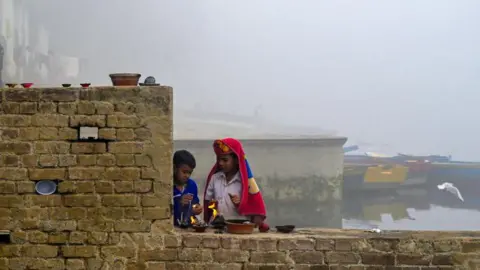 Getty Images Boys light lamps on a brick wall on a bank of the river Yamuna in Delhi. Smog engulfs their surroundings