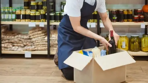 Getty Images Generic image of shop worker stocking shelves
