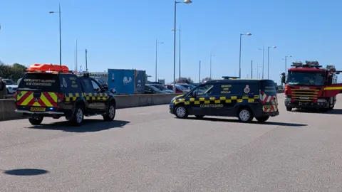 Wirral Coastguard Rescue Team Two Coastguard vehicles and a fire engine parked on King Parade in New Brighton to assist with a rescue of a woman on New Brighton beach. It was a sunny day.