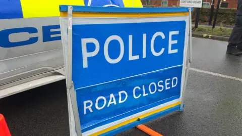Police road closed sign on the road at the Coxford Road entrance of the hospital