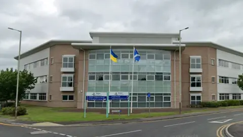 Angus Council's headquarters in Forfar, a two-storey building with a glass front and flags flying in front