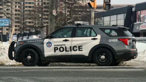 A Toronto police vehicle drives past piles of snow by a main road in Toronto, Ontario, Canada, on February 22, 2025.