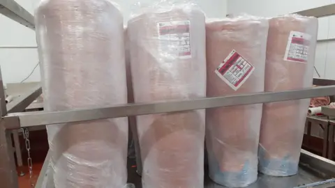 Swansea Trading Standards Four pink looking uncooked donor kebabs all wrapped in cling film standing on a trolley in a food processing factory
