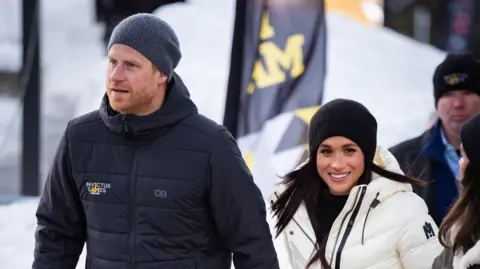 PA Media The Duke and Duchess of Sussex attending the 2025 Invictus Games in Vancouver this month. Harry is wearing a blue Invictus Games coat and woolly hat. Meghan is wearing a black woolly hat an white coat.