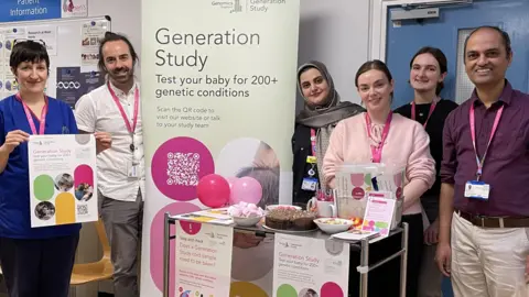 West Hertfordshire Teaching Hospitals NHS Trust Six hospital staff wearing lanyards stand next to a banner promoting 'Generation Study'. 
