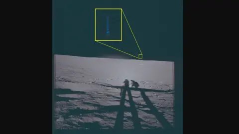 A photo from the surface of the Moon. It shows the shadows of two astronauts, and in the distance what looks like a flash of blue light. It is highlighted and englarged