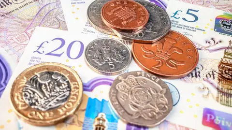 Getty Images UK bank notes and coins are lying on a flat surface. 
