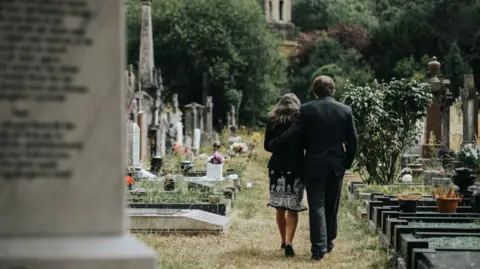 A man and woman walking in a graveyard